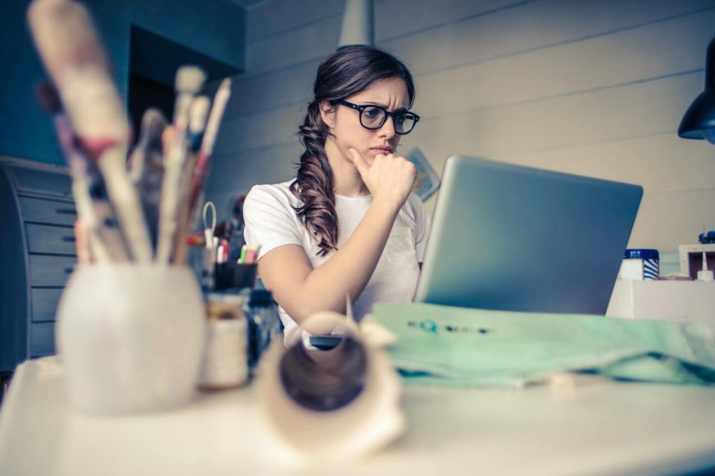 A woman thinking in front of a computer which shows the signs your ex is thinking about you